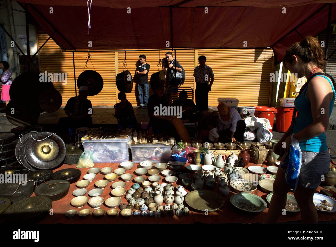 Un turista che presta attenzione alla porcellana presso un venditore durante il mercato domenicale di Gaya, una fiera settimanale e un mercato di strada situato in Gaya Street, Kota Kinabalu, Sabah, Malesia. Foto Stock