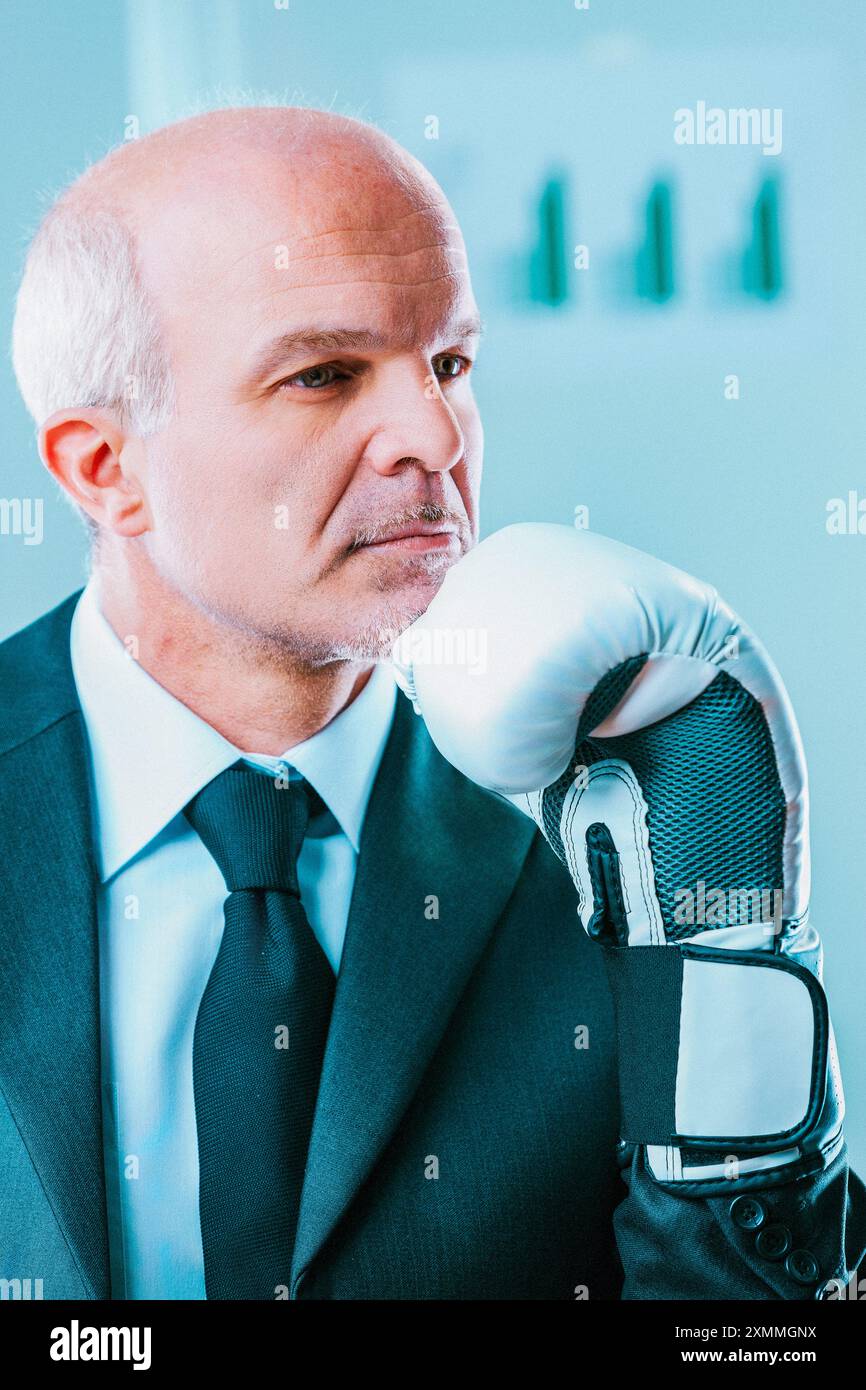 Un uomo d'affari attento indossa un guanto da boxe, che simboleggia le sfide e il pensiero strategico richiesti nel mondo degli affari Foto Stock