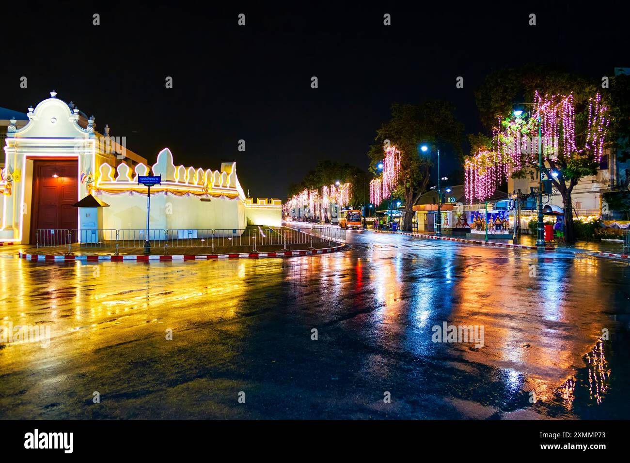 Pareti illuminate di notte del Grand Palace e treea lungo la strada, Bangkok, Thailandia Foto Stock