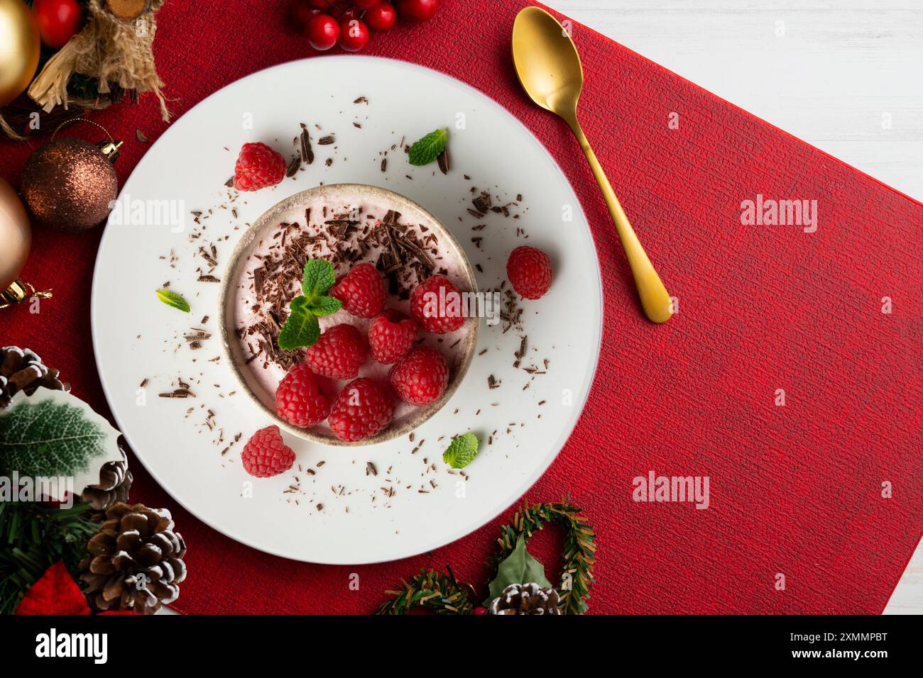 Deliziosa mousse di lamponi con frutti rossi da una prospettiva sopraelevata. Tavolo con decorazioni natalizie. Foto Stock