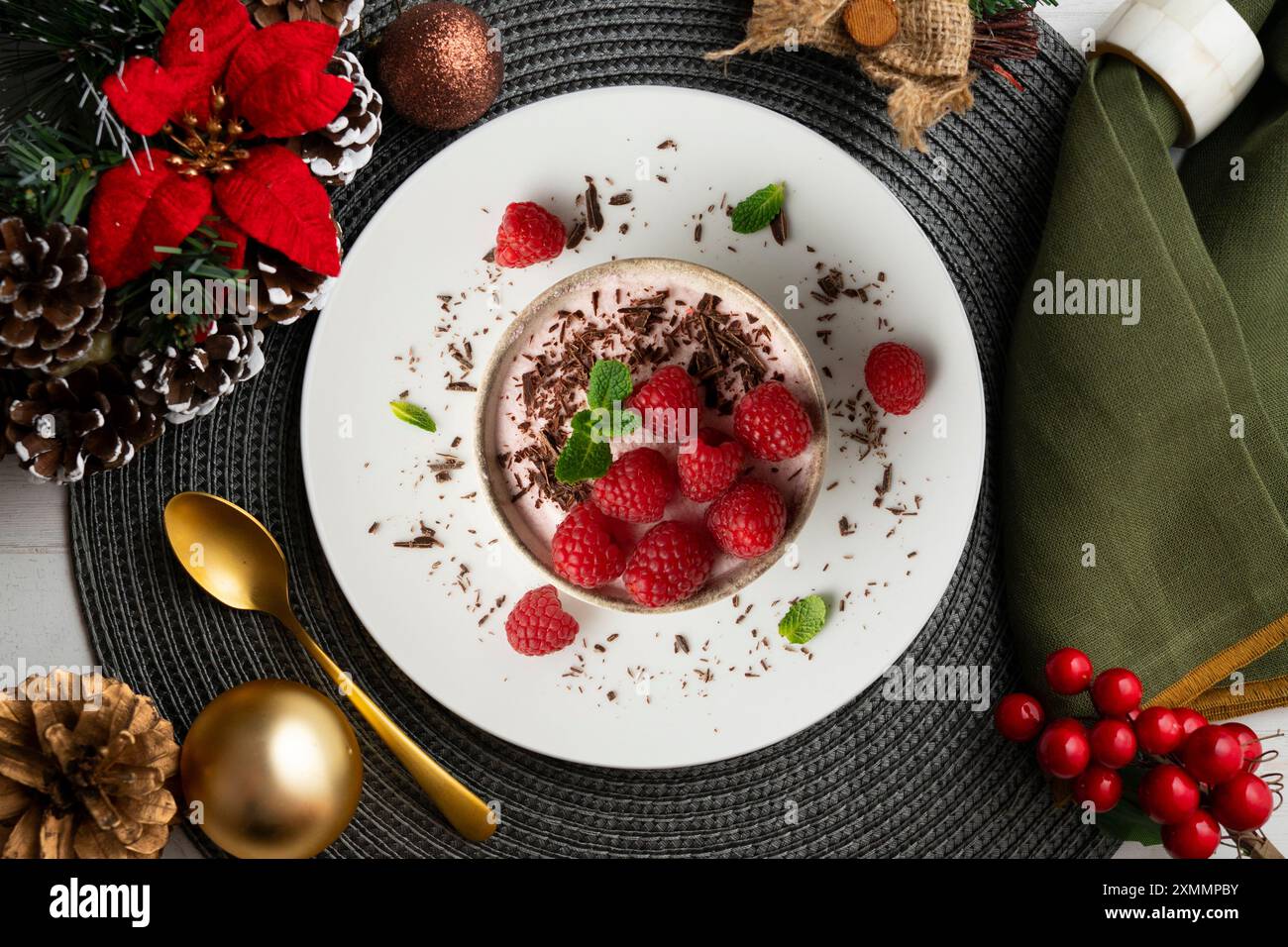 Deliziosa mousse di lamponi con frutti rossi da una prospettiva sopraelevata. Tavolo con decorazioni natalizie. Foto Stock