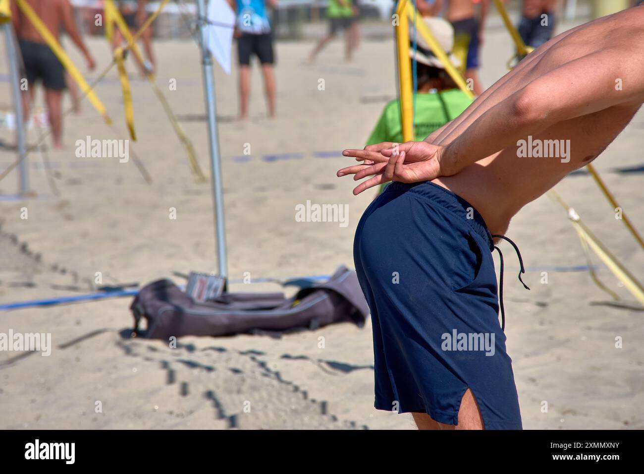 Un giocatore di Beach volley invia segnali a mano per comunicare con i compagni durante un'intensa partita 3x3. Questa immagine ricca di azione cattura la strategia Foto Stock