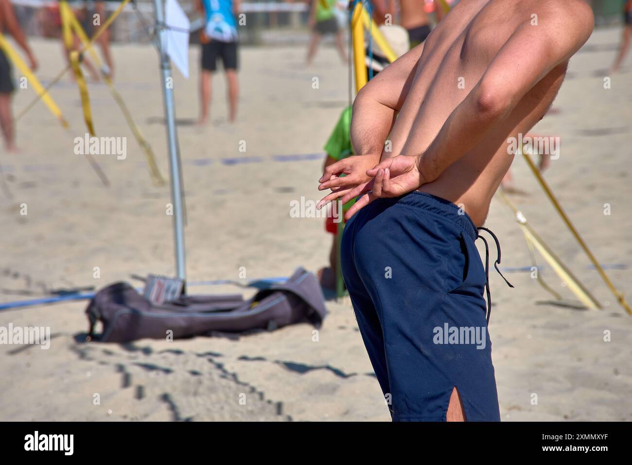 Un giocatore di Beach volley invia segnali a mano per comunicare con i compagni durante un'intensa partita 3x3. Questa immagine ricca di azione cattura la strategia Foto Stock