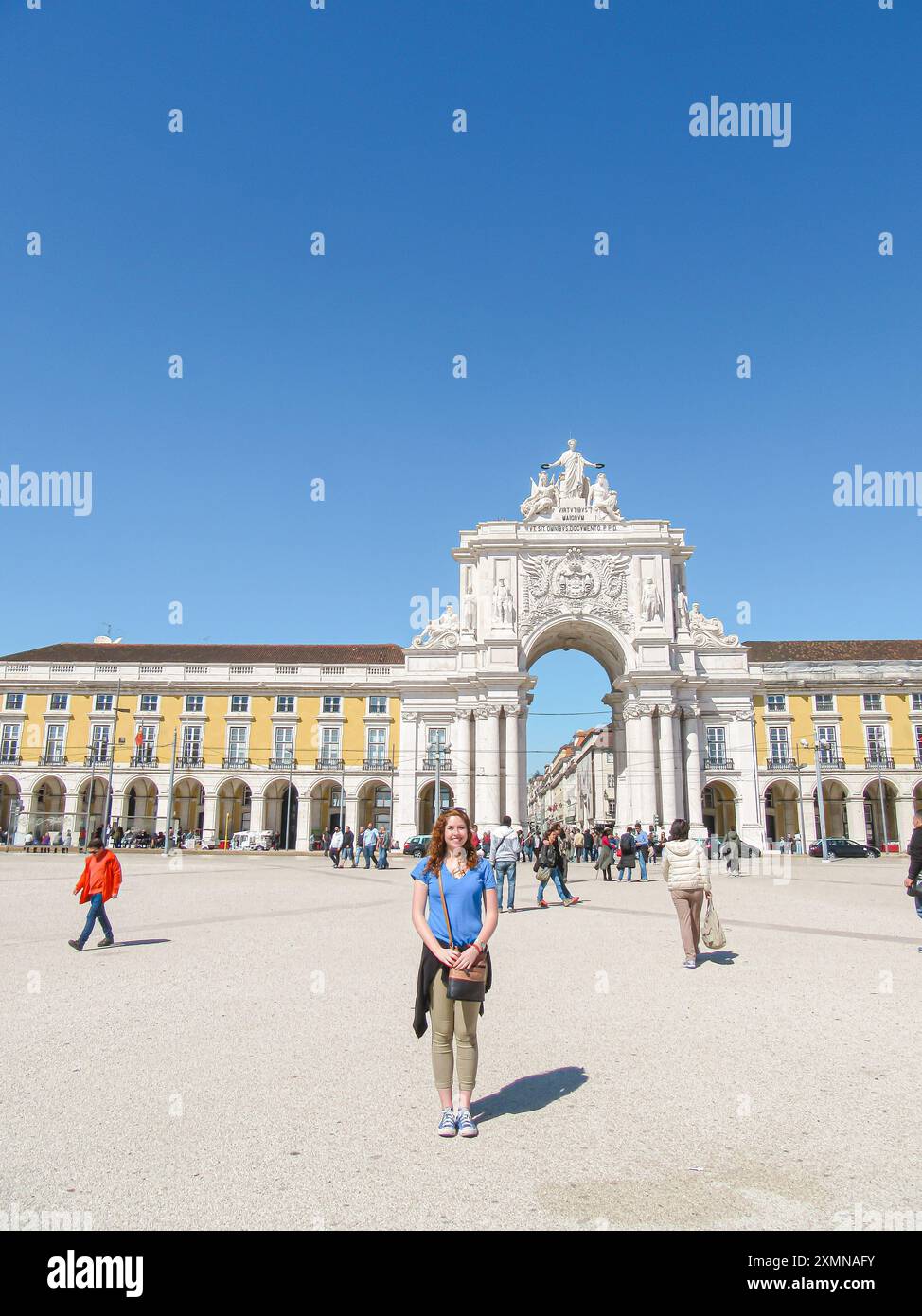 Donna in piedi in una piazza europea con dietro un arco storico Foto Stock