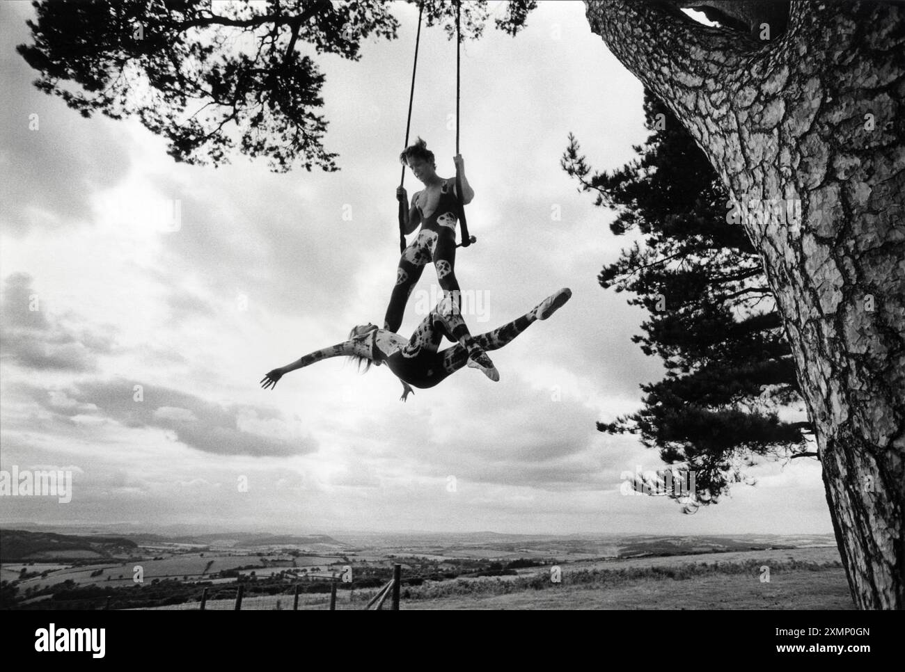 Gli artisti del trapezio del circo Andrew Watson e Jacqueline Williams provano il loro atto in un bosco a May Hill nella foresta di Dean. Furono costretti a praticare fuori sugli alberi perché non potevano ottenere un'assicurazione per coprire il loro uso della palestra locale. equilibrio, grazia, portamento, surreale. Foto Stock