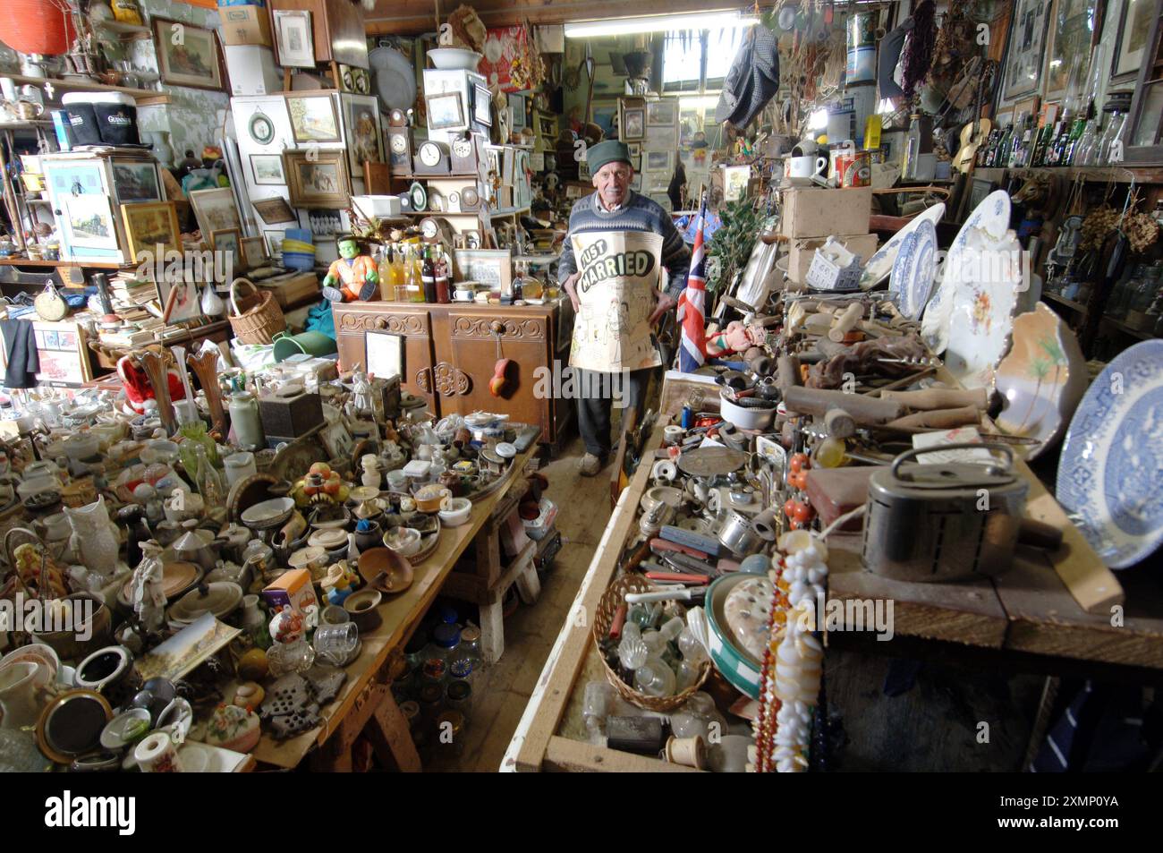 Foto di Roger Bamber: 5 febbraio 2006: Il costruttore in pensione William Brett esamina alcuni dei suoi migliaia di manufatti raccolti nel corso degli anni nelle ex aule della sua vecchia casa scolastica a Calbourne, Isola di Wight, perché non getta mai nulla. Nascosti sotto gli innumerevoli pezzi di Bric a Brac ci sono la sua vecchia scrivania scolastica, un motociclo della BSA, maschere antigas per bambini in tempo di guerra, la bicicletta per la consegna dei supermercati, un banco di fucili dei garisons in tempo di guerra, innumerevoli macchinine giocattolo al piombo, i cartelli del pub locale e della stazione di polizia e centinaia di bottiglie di vino Foto Stock