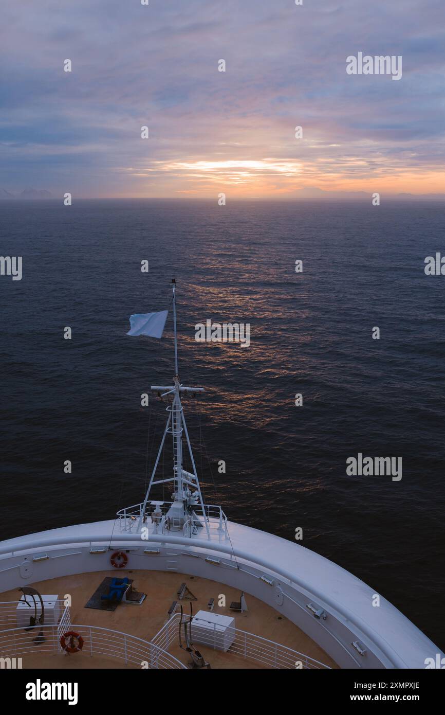 Nave da crociera bandiera bianca Bow of Ship Sails al tramonto con disposizione verticale Horizon. Viaggio avventura nelle acque azzurre calde Foto Stock