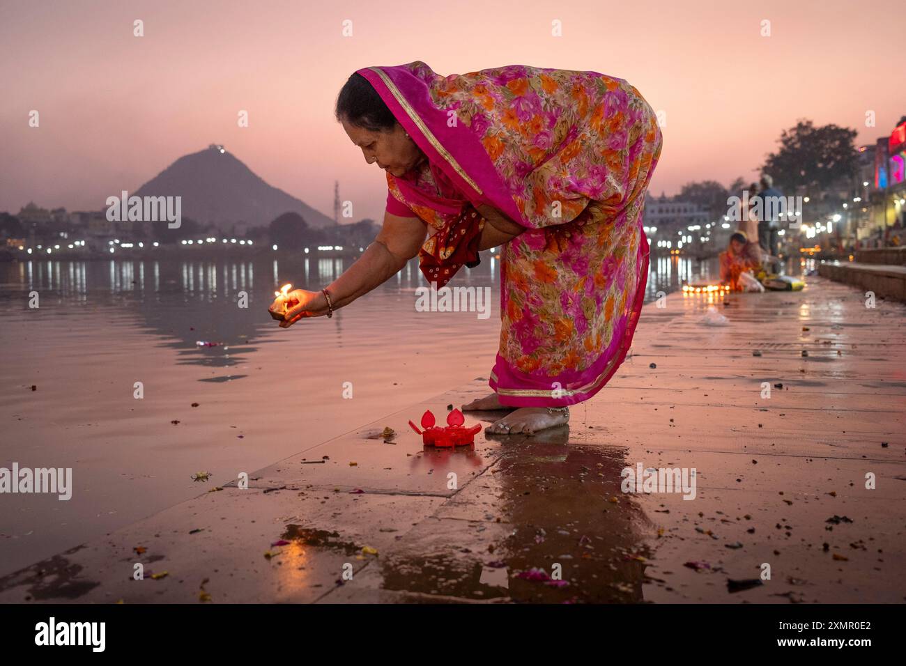 Una donna accende una candela lungo il lago Puskar durante Pushkar Camel Fair, Pushkar, Rajasthan, India, Asia Foto Stock