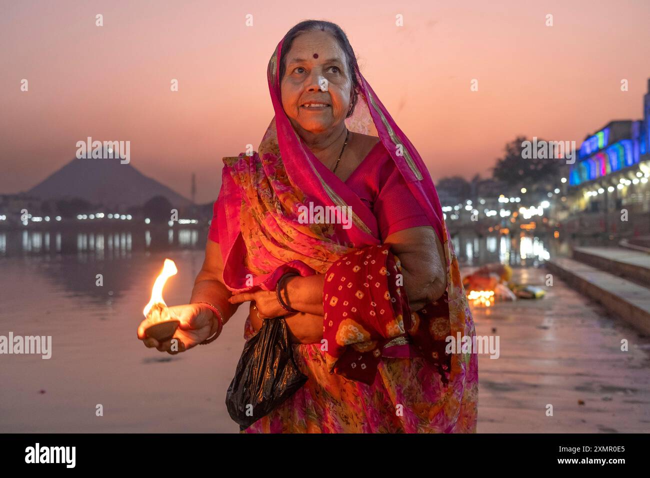 Una donna accende una candela lungo il lago Puskar durante Pushkar Camel Fair, Pushkar, Rajasthan, India, Asia Foto Stock