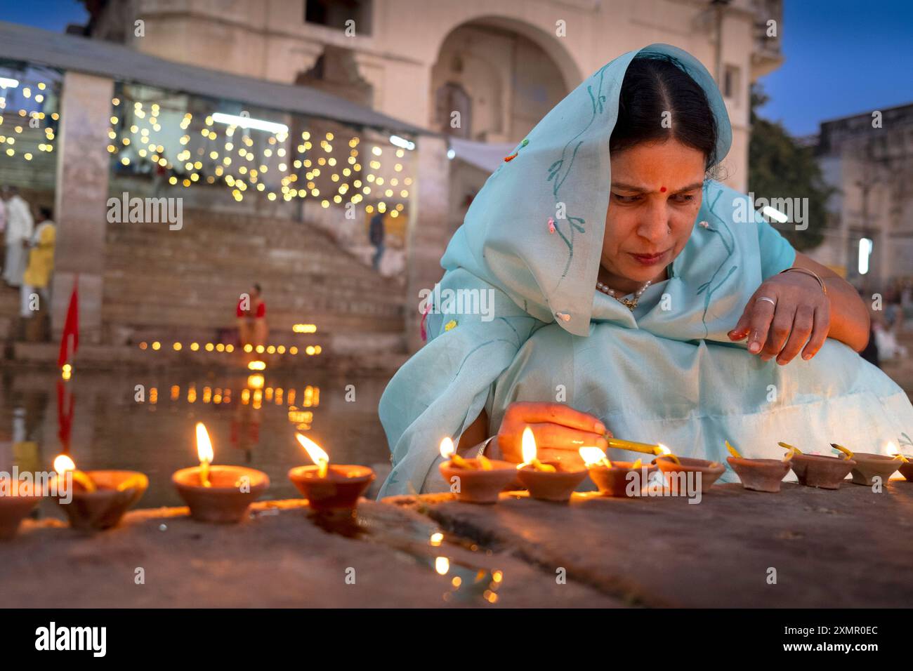 Una donna accende le candele puja lungo il lago Puskar durante Pushkar Camel Fair, Pushkar, Rajasthan, India, Asia Foto Stock