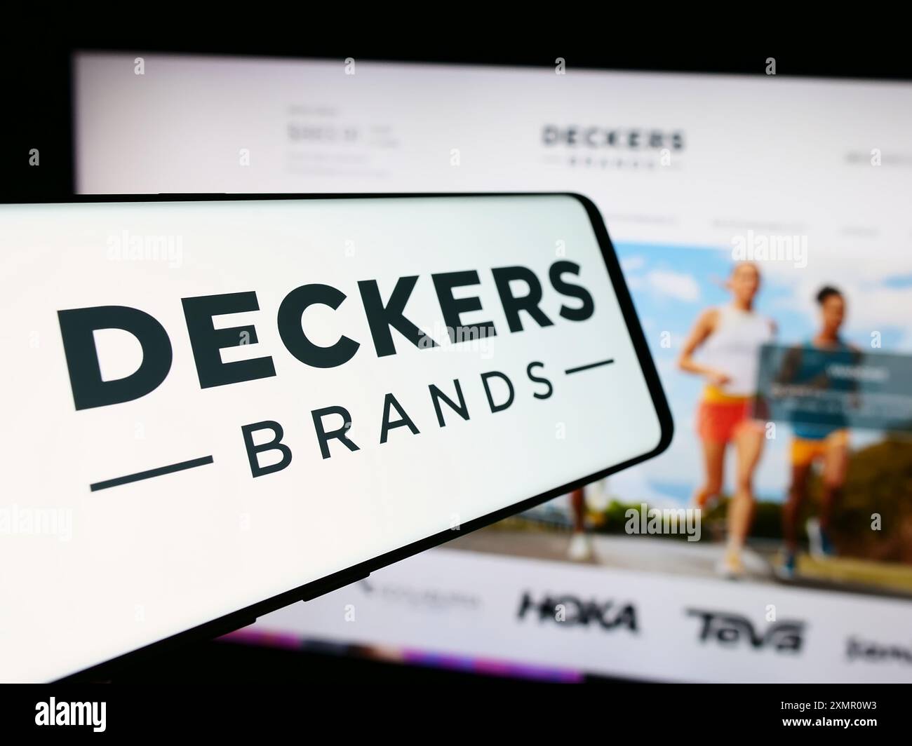 Telefono cellulare con logo dell'azienda americana di calzature Deckers Outdoor Corporation davanti al sito Web. Mettere a fuoco la parte centrale sinistra del display del telefono. Foto Stock