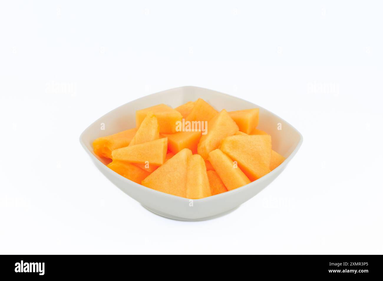 Fette di melone in una ciotola bianca isolata su sfondo bianco. Foto Stock