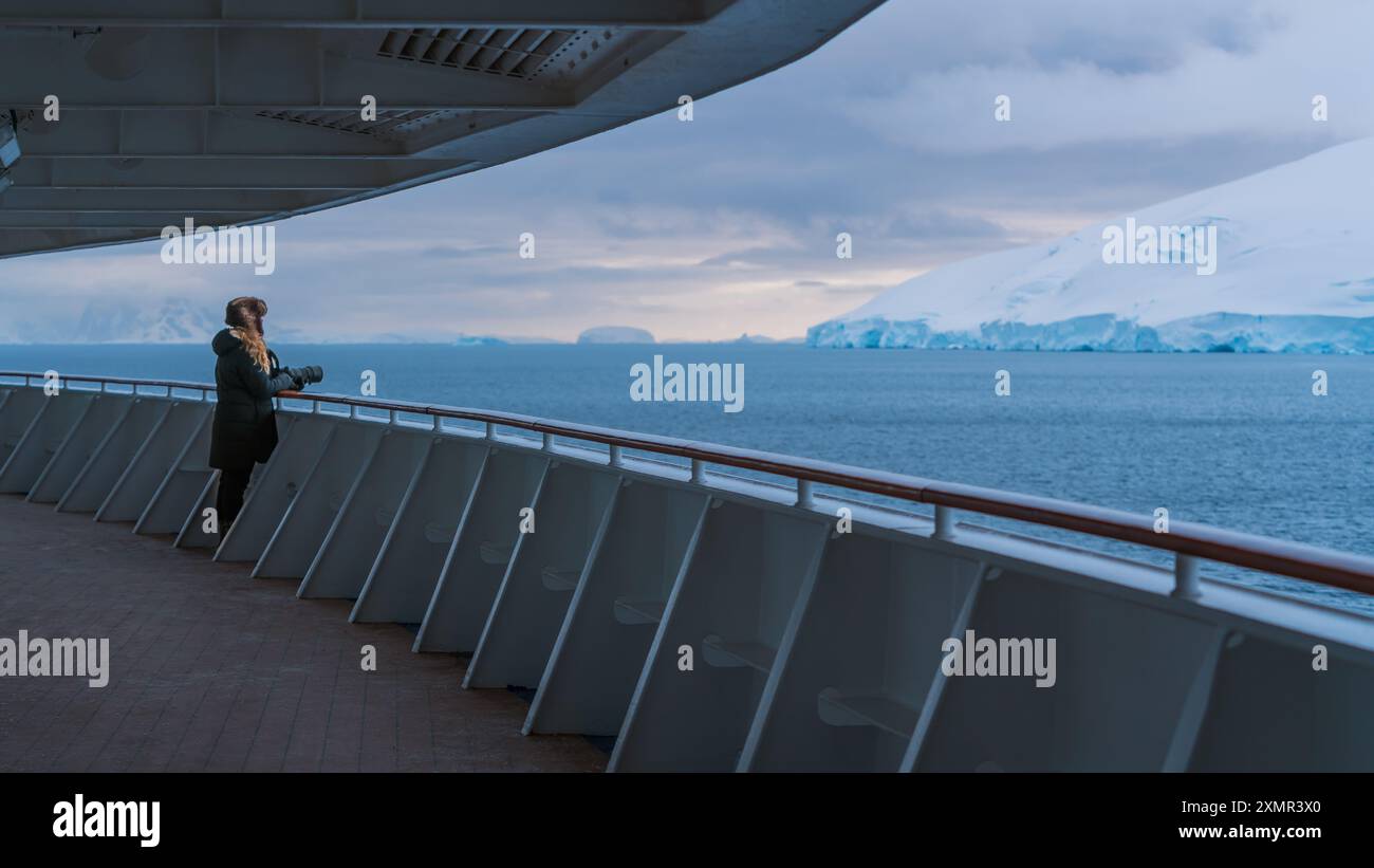 Una bellissima fotografa femminile sul ponte Promenade della nave da crociera Antartide ha un'immagine da fotocamera professionale che ti stupisce per gli Iceberg e i ghiacciai Foto Stock