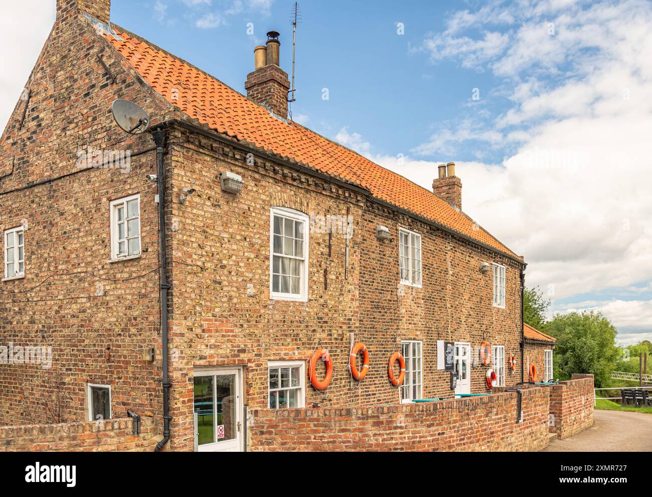 Un edificio in mattoni, ora un ristorante e pub, situato vicino a un canale chiuso sul fiume Ouse nello Yorkshire. Le cinture di salvataggio sono appese alle pareti e al cielo Foto Stock