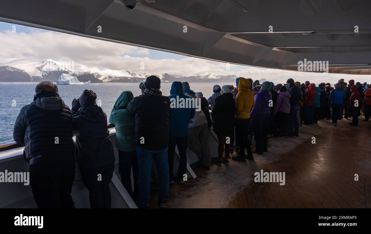 Deception Island, Antartide - 29 dicembre 2023: Foto dalla nave da crociera di gruppo di passeggeri che osservano Terra, Iceberg, ghiacciai da Side Railing Foto Stock