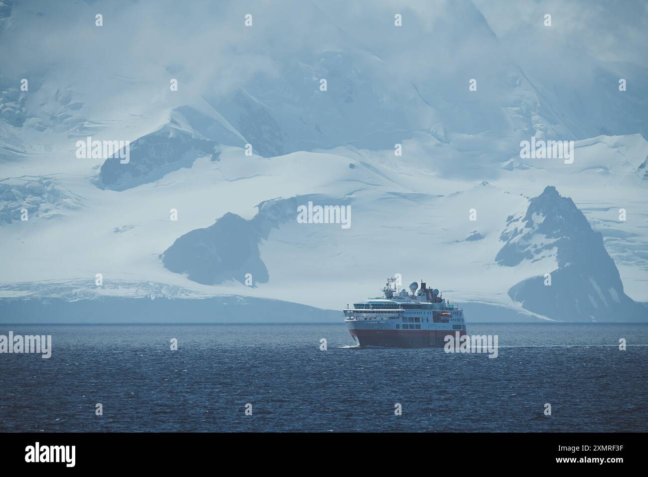 Nave da spedizione Antartide con enormi montagne coperte di neve destinazione remota crociera panoramica ampia vista esplorando l'Artico Foto Stock