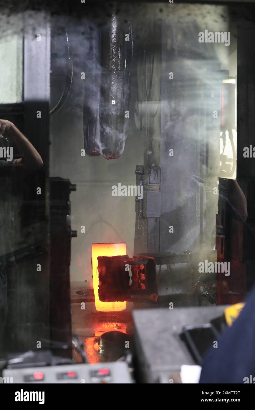 Il processo automatizzato consente di spostare le billette calde dal forno alla pressa per la fase successiva del processo di produzione delle casse di proiettile, in cui le billette riscaldate vengono inviate da un nastro trasportatore a tre presse separate. La prima stampa lo perfora. La seconda pressa la estrude. E la terza pressa estrae il metallo fino alla sua lunghezza finale di circa 30 pollici. (Foto U.S. Army, Scranton Army Ammunition Plant, di Eben Boothby, U.S. Army Materiel Command) Foto Stock