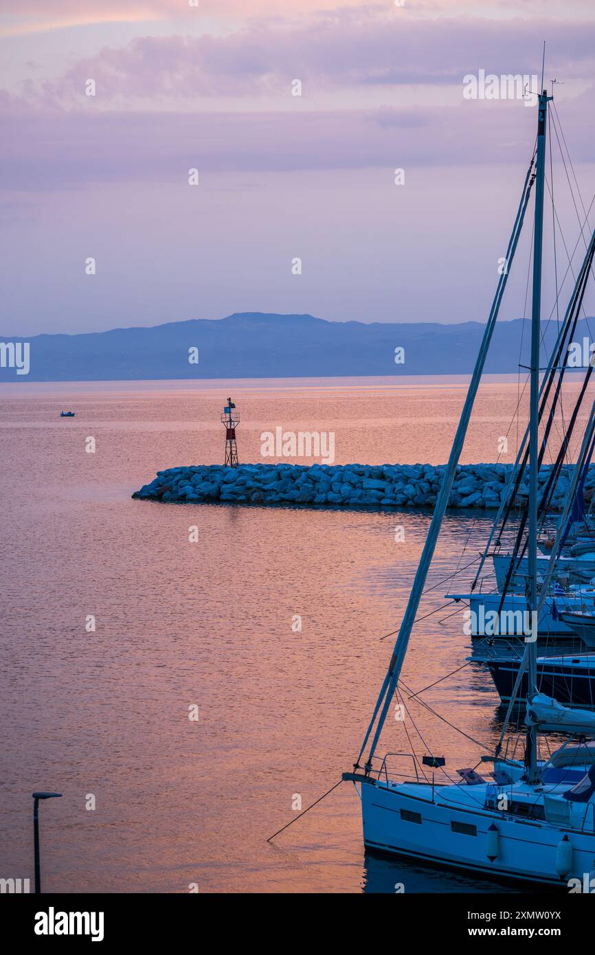 Vista panoramica di un tranquillo paesaggio costiero caratterizzato da acque calme e colline lontane sotto un cielo crepuscolo Foto Stock