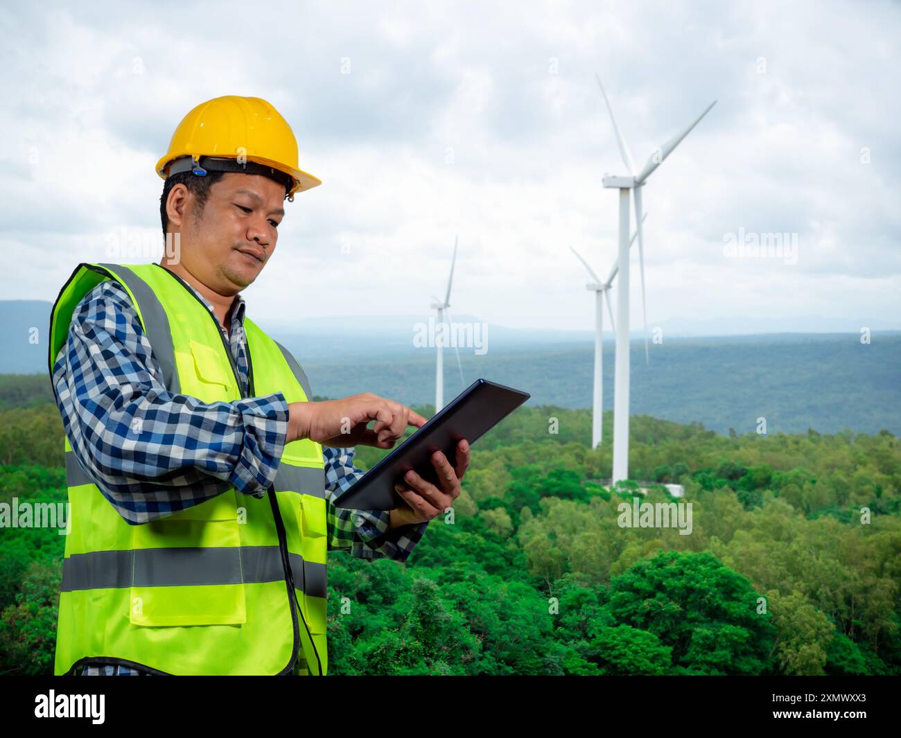 Ingegnere che controlla l'energia elettrica di controllo, ingegnere che lavora con tablet presso un impianto di produzione di energia elettrica pulita, generatore di turbine eoliche Foto Stock