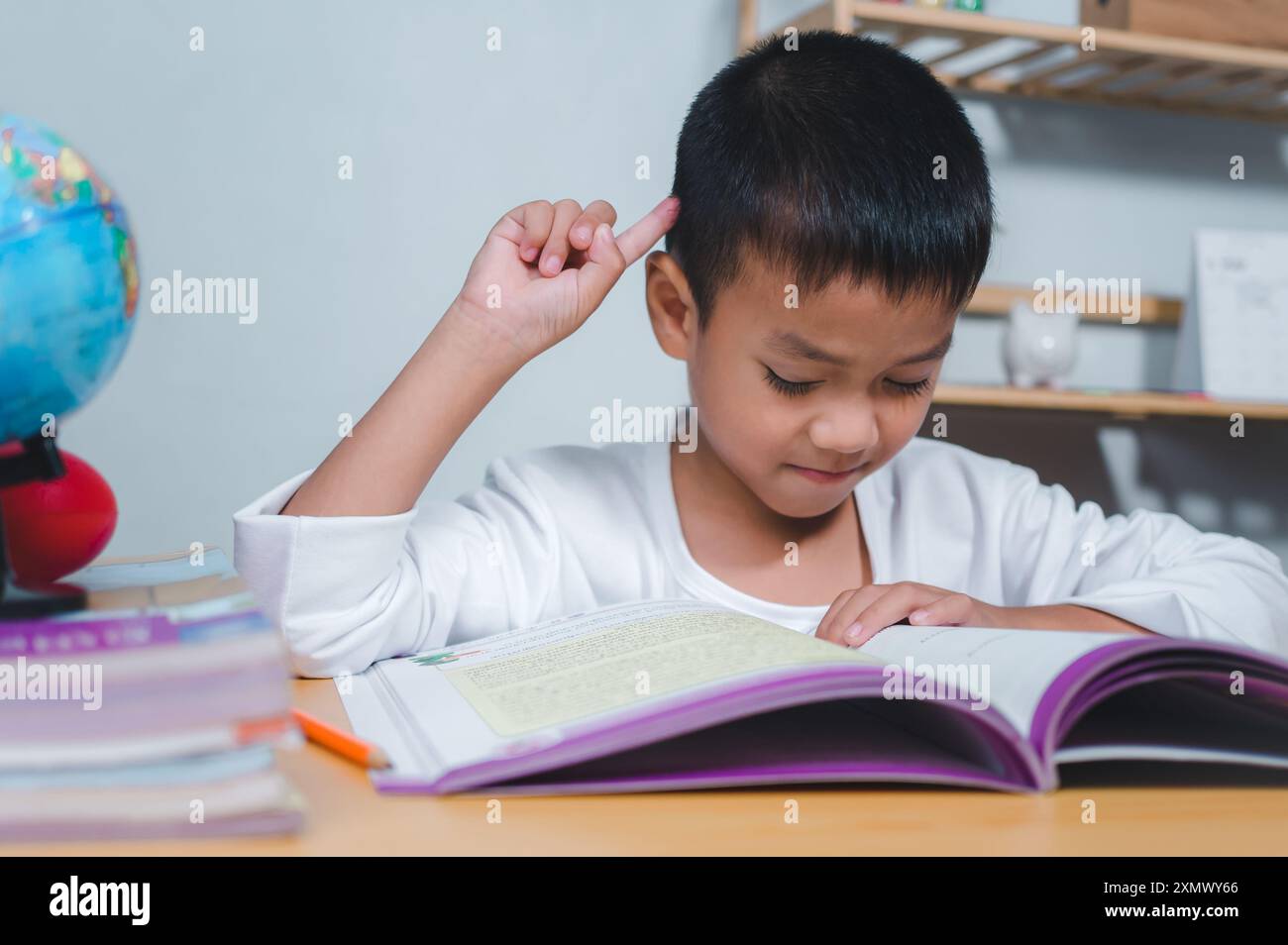 Concetto educativo, ragazzo triste stanco frustrato seduto al tavolo con molti libri, ragazzo annoiato e stanco che fa i compiti sulla scrivania nella sua stanza, imparando dif Foto Stock