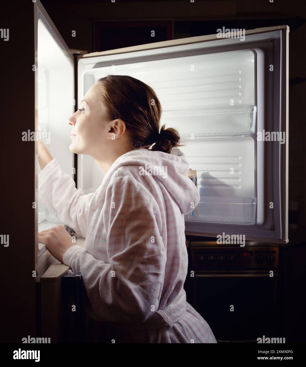 Giovane donna in cerca di uno spuntino in frigo a tarda notte Foto Stock