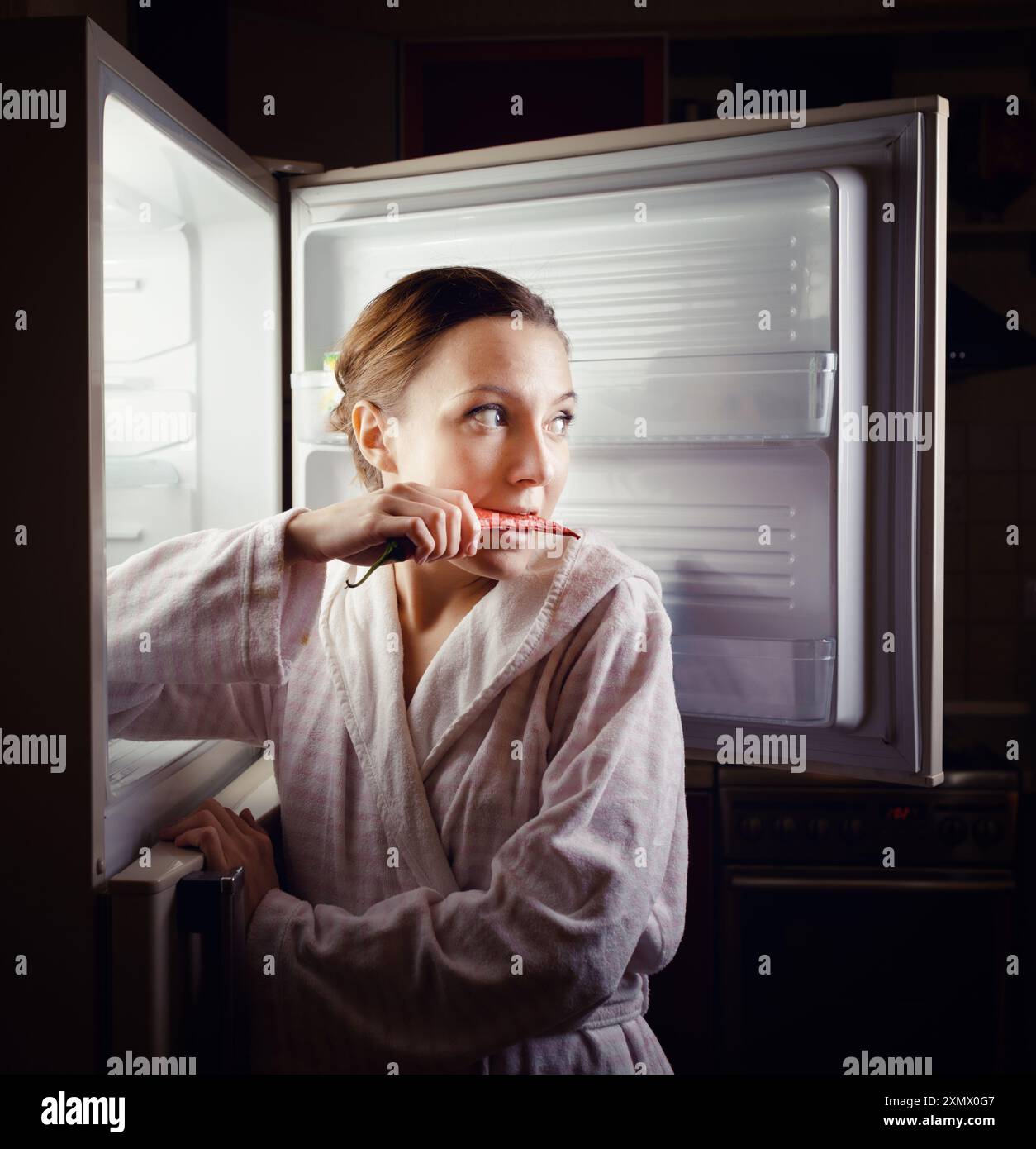 Giovane donna in cerca di uno spuntino in frigo a tarda notte Foto Stock