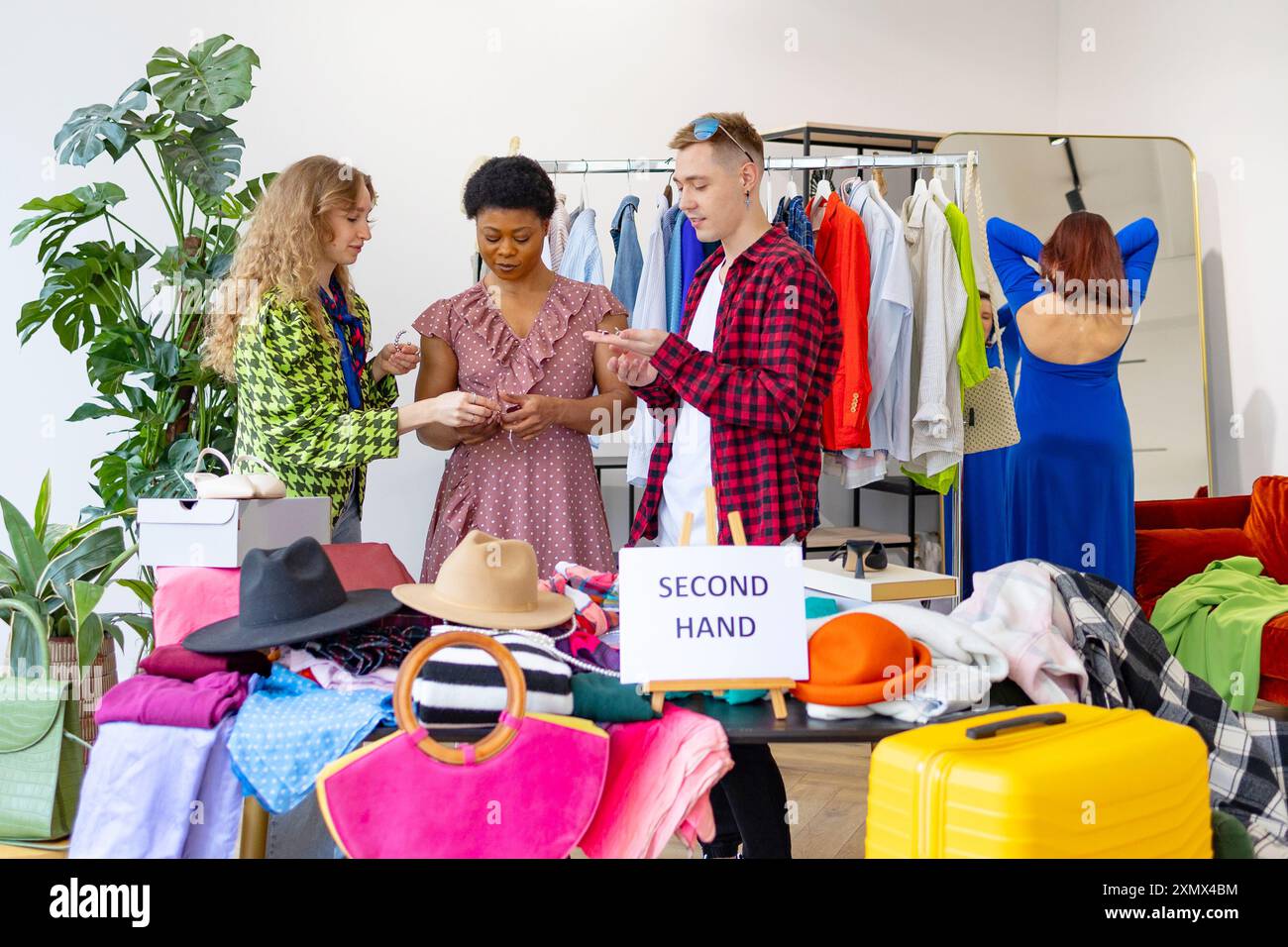 negozio di seconda mano, risparmiando denaro e budget per la famiglia, i giovani studenti alla festa di scambio provano vestiti, borse, scarpe e accessori, cambiano vestiti con spirito Foto Stock