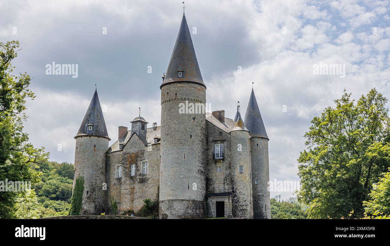 Castello di Veves con mura in pietra con le sue torri con tetti conici, circondato da verdi alberi frondosi, cielo grigio tempestoso sullo sfondo, giorno di sole a Houyet, Foto Stock