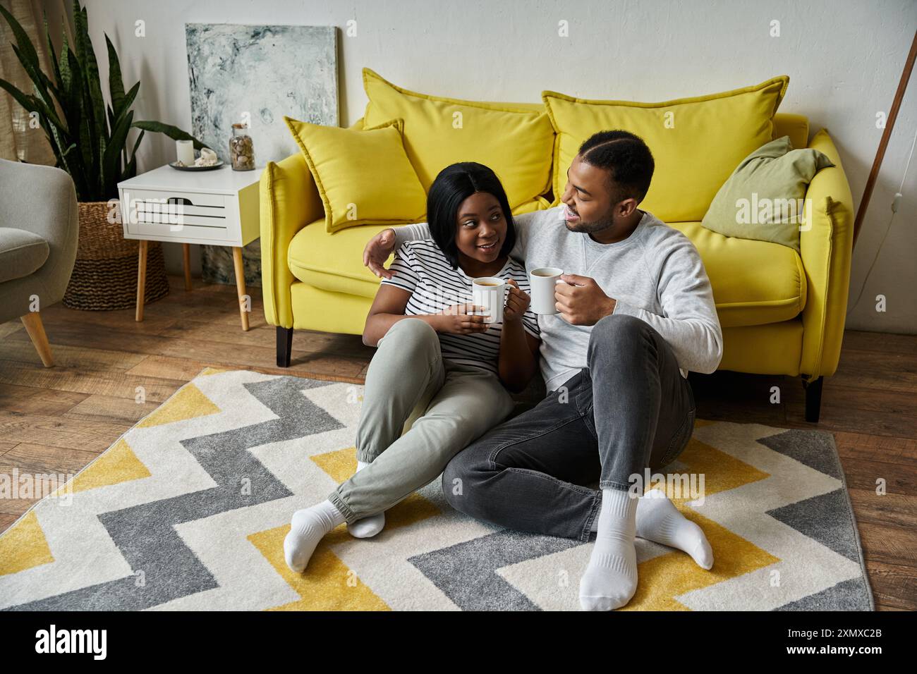 Una coppia afroamericana ama trascorrere un momento di relax insieme a casa, condividendo una tazza di caffè. Foto Stock