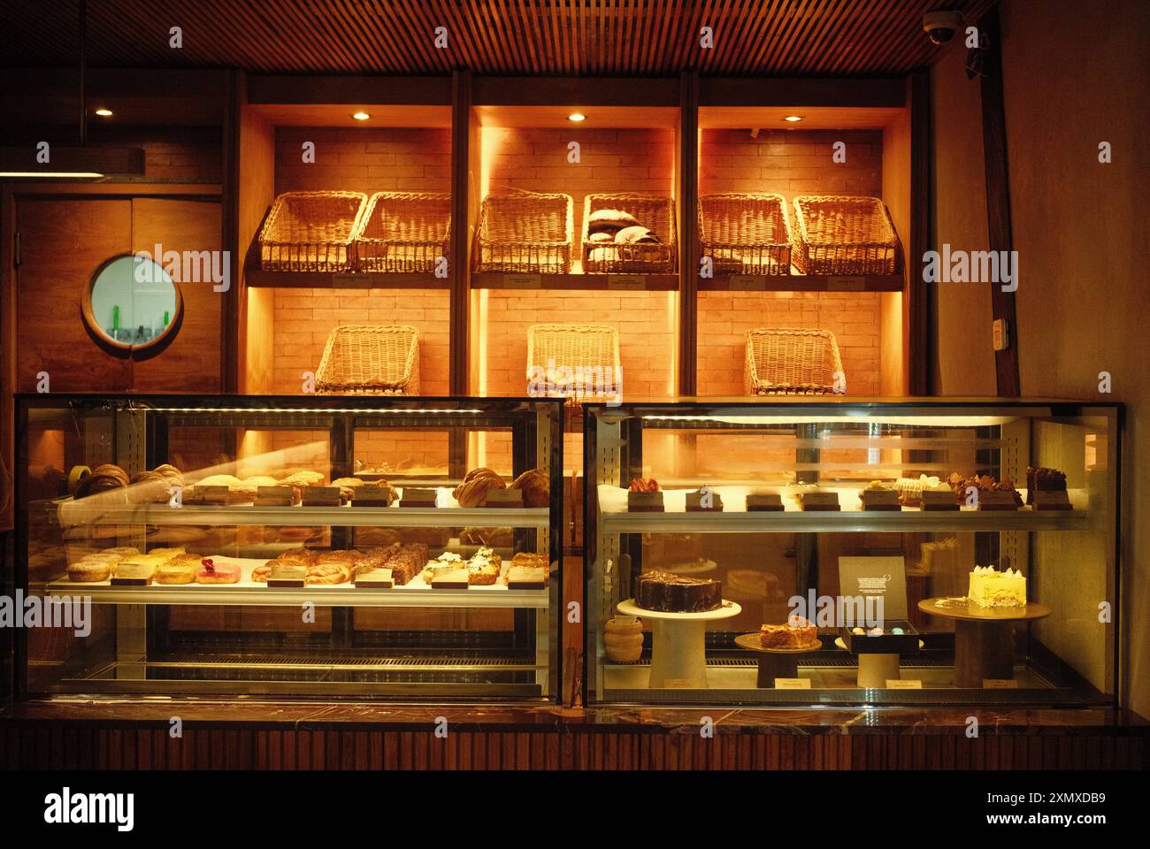 Ubud, Bali, Indonesia - 9 luglio 2024: Interni del Cafe con una panetteria e un'esposizione di torte, caratterizzate da un'architettura estetica moderna e da una calda illuminazione Foto Stock