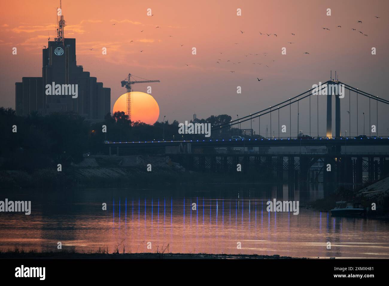 Il sole tramonta dietro il Babylon Hotel e il 14 luglio Ponte sospeso a Baghdad, Iraq - 5 febbraio 2023 Foto Stock