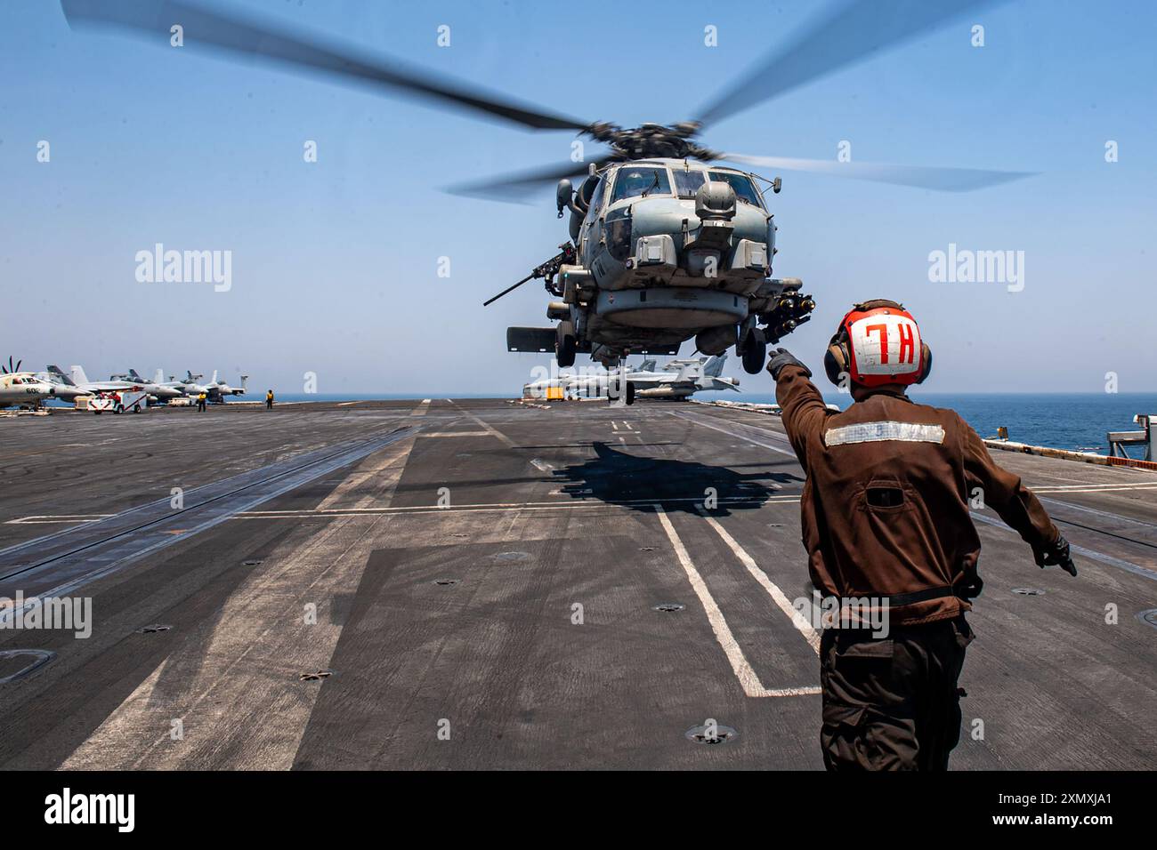 5TH FLEET AREA OF OPERATIONS (25 luglio 2024) un Aviation Machinist's Mate dirige un elicottero MH-60R Sea Hawk, attaccato alla Helicopter Maritime Foto Stock