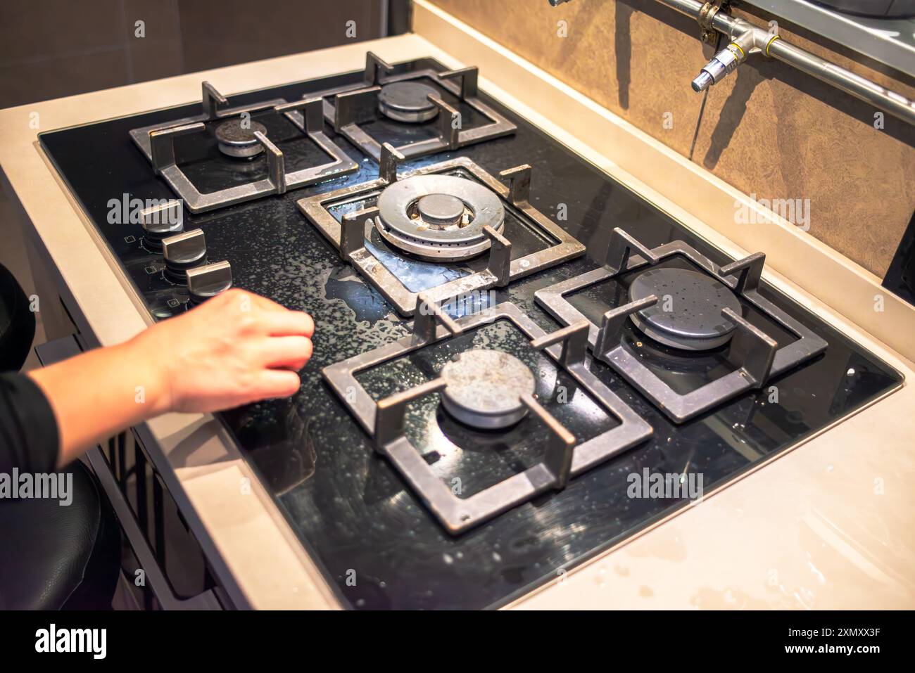 Un cuoco che tenta di accendere il fornello, mostrando l'azione di cottura della stufa durante il processo di cottura in un ambiente di cucina affollato. Foto Stock