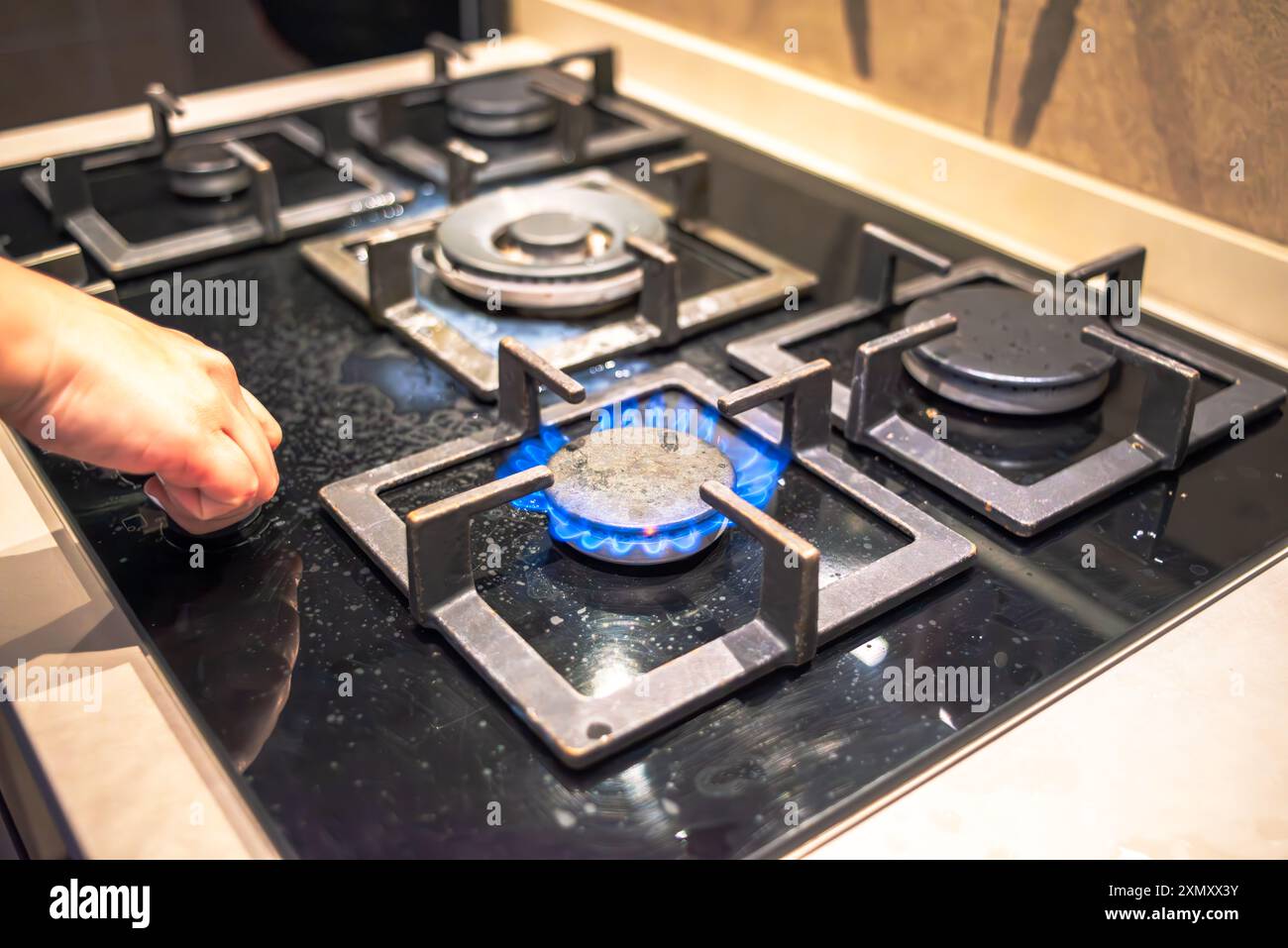 Un cuoco che tenta di accendere il fornello, mostrando l'azione di cottura della stufa durante il processo di cottura in un ambiente di cucina affollato. Foto Stock