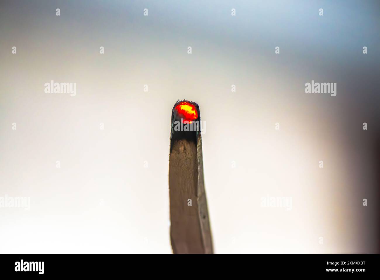 Una foto macro che cattura i dettagli intricati e il brillante bagliore di due pezzi di legno di Palo Santo in fiamme, evidenziando il fumo aromatico e la b naturale Foto Stock