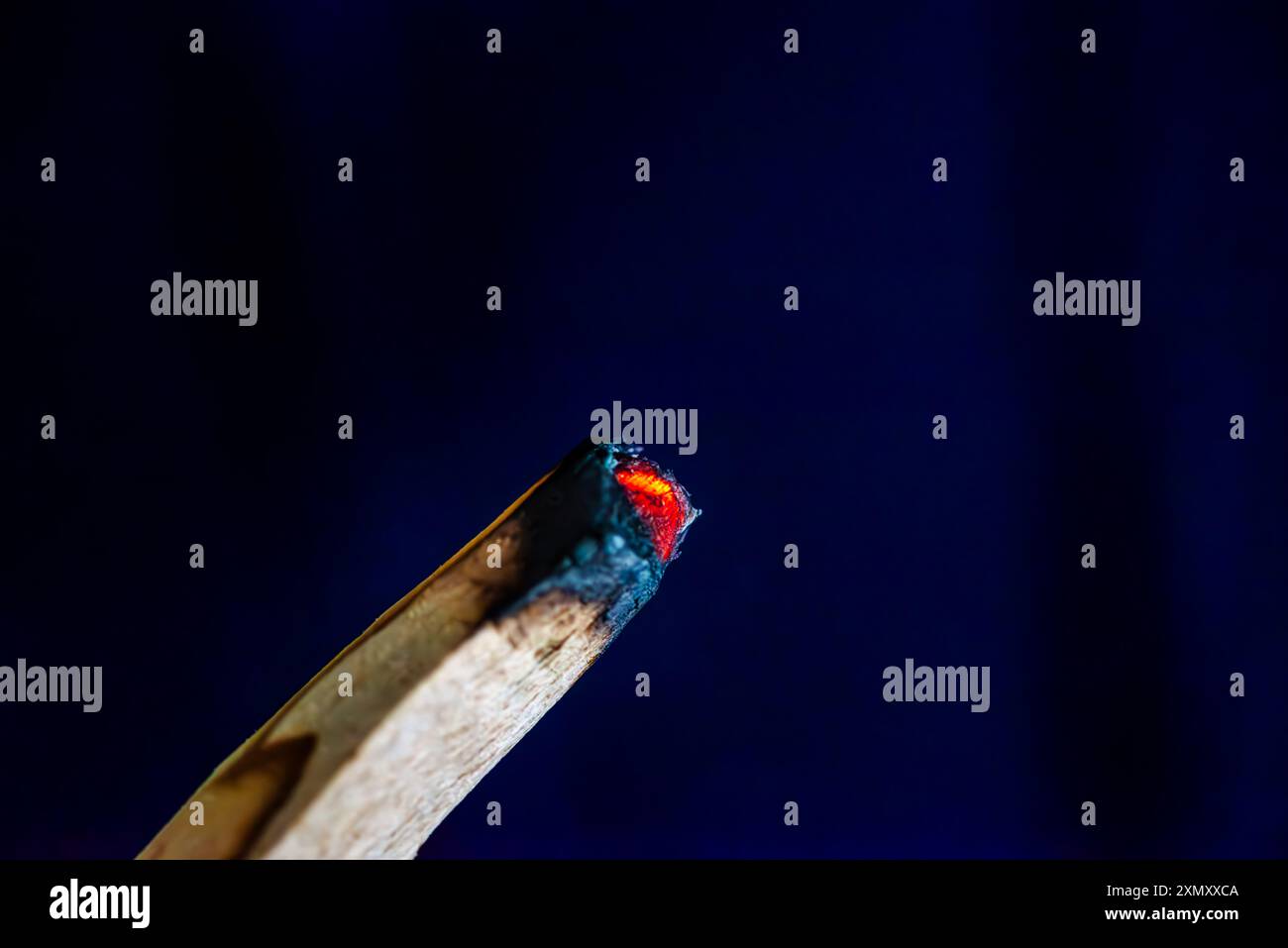 Una foto macro che cattura i dettagli intricati e il brillante bagliore di due pezzi di legno di Palo Santo in fiamme, evidenziando il fumo aromatico e la b naturale Foto Stock