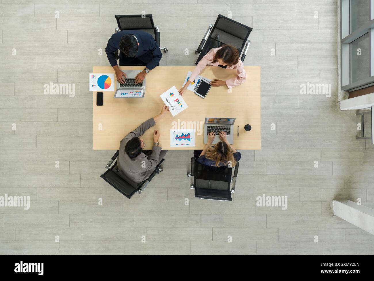 Un team di lavoratori è seduto insieme a un grande tavolo in un ufficio, condividendo pensieri e parlando. Vista dall'alto Foto Stock