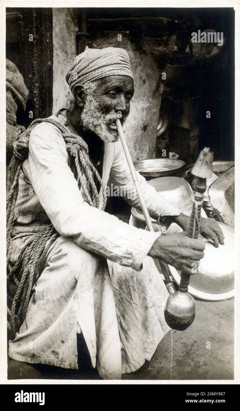 Uomo egiziano che fuma una pipa Hookah a gambo lungo Foto Stock
