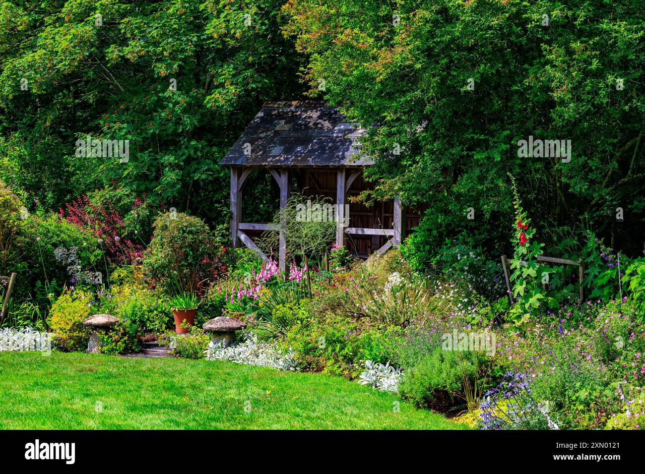 Una casa estiva in legno e un colorato confine erbaceo al Docton Mill Garden, Lymebridge, North Devon, Inghilterra, Regno Unito Foto Stock