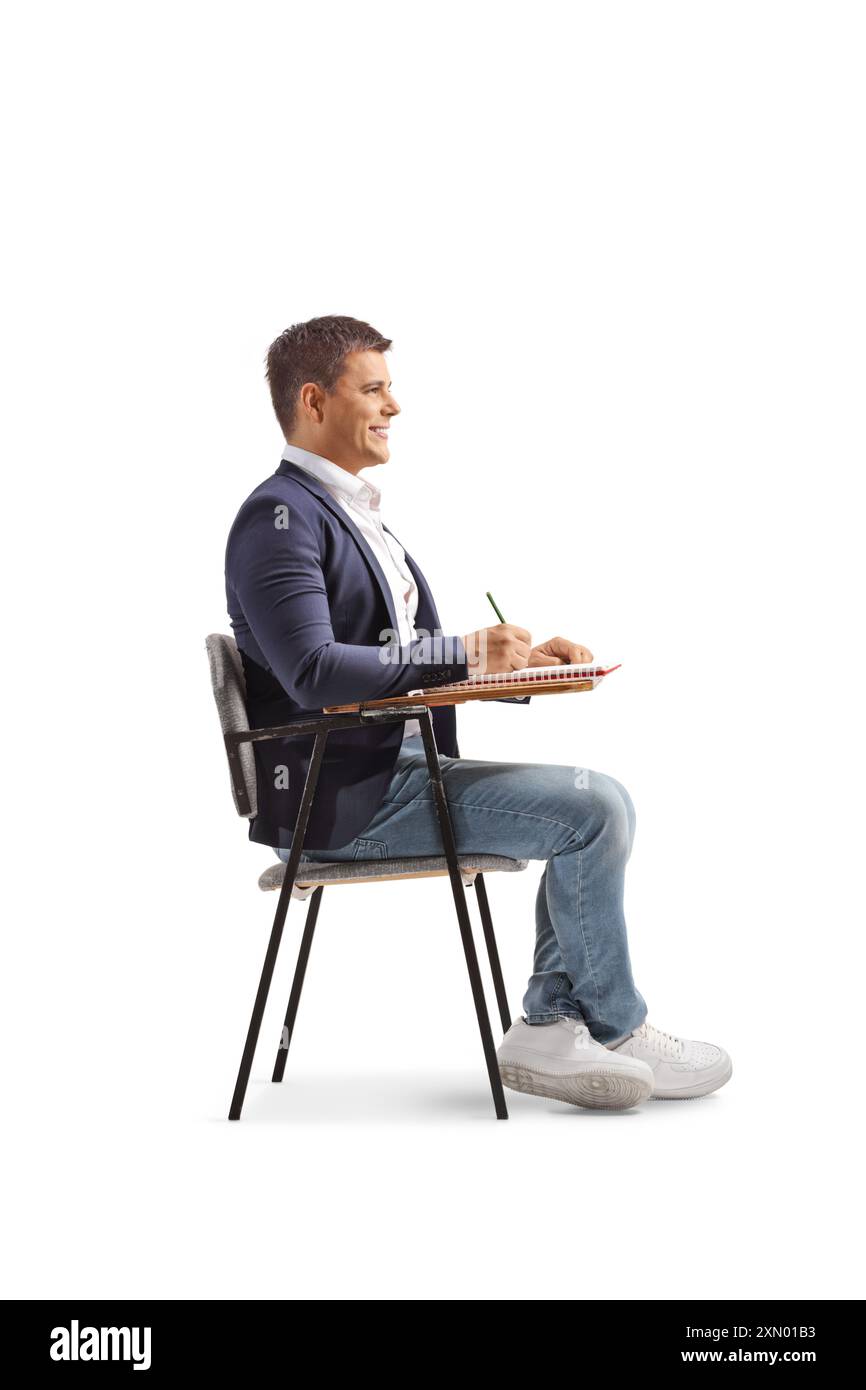 Uomo seduto su una sedia scolastica e a scrivere isolato su sfondo bianco Foto Stock