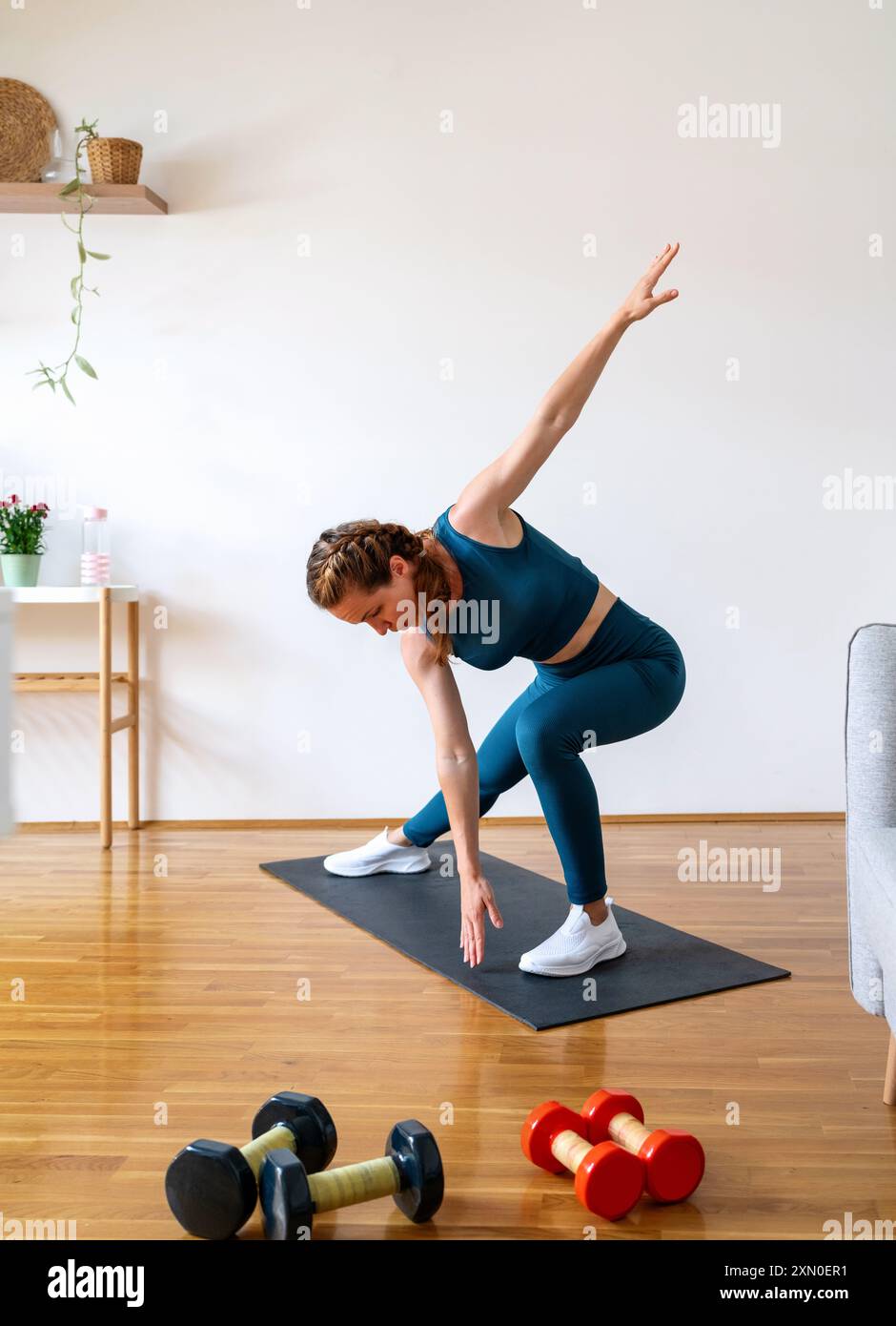 Donna caucasica atletica che indossa abbigliamento sportivo per allenarsi a casa. Foto Stock