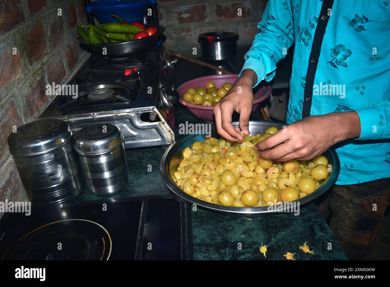 Un ragazzo indiano che toglie i semi dalla spina per fare caramelle, concetto di cucina Foto Stock