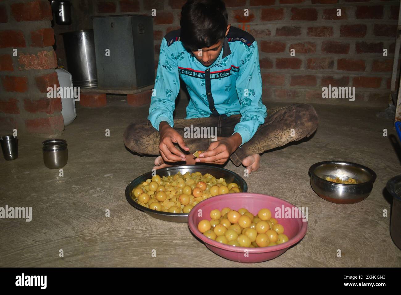 Un ragazzo indiano che toglie i semi dalla spina per fare caramelle, concetto di cucina Foto Stock
