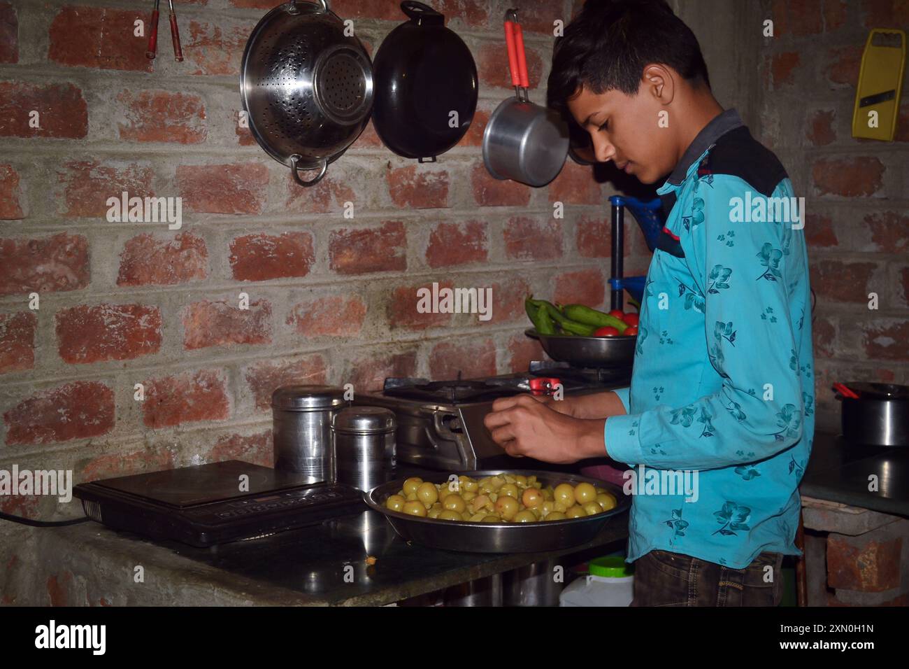 Un ragazzo indiano che toglie i semi dalla spina per fare caramelle, concetto di cucina Foto Stock