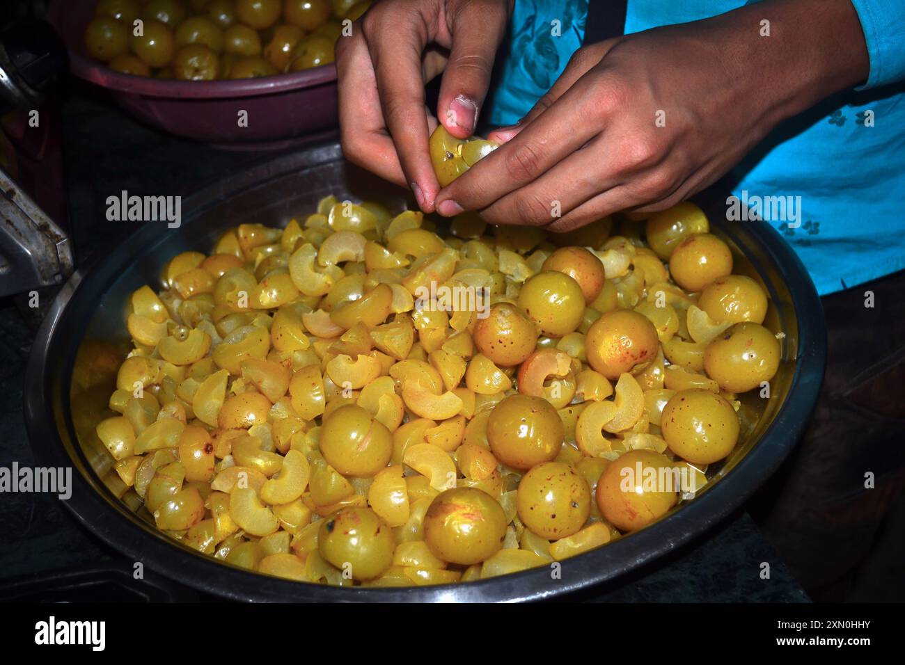 Un ragazzo indiano che toglie i semi dalla spina per fare caramelle, concetto di cucina Foto Stock