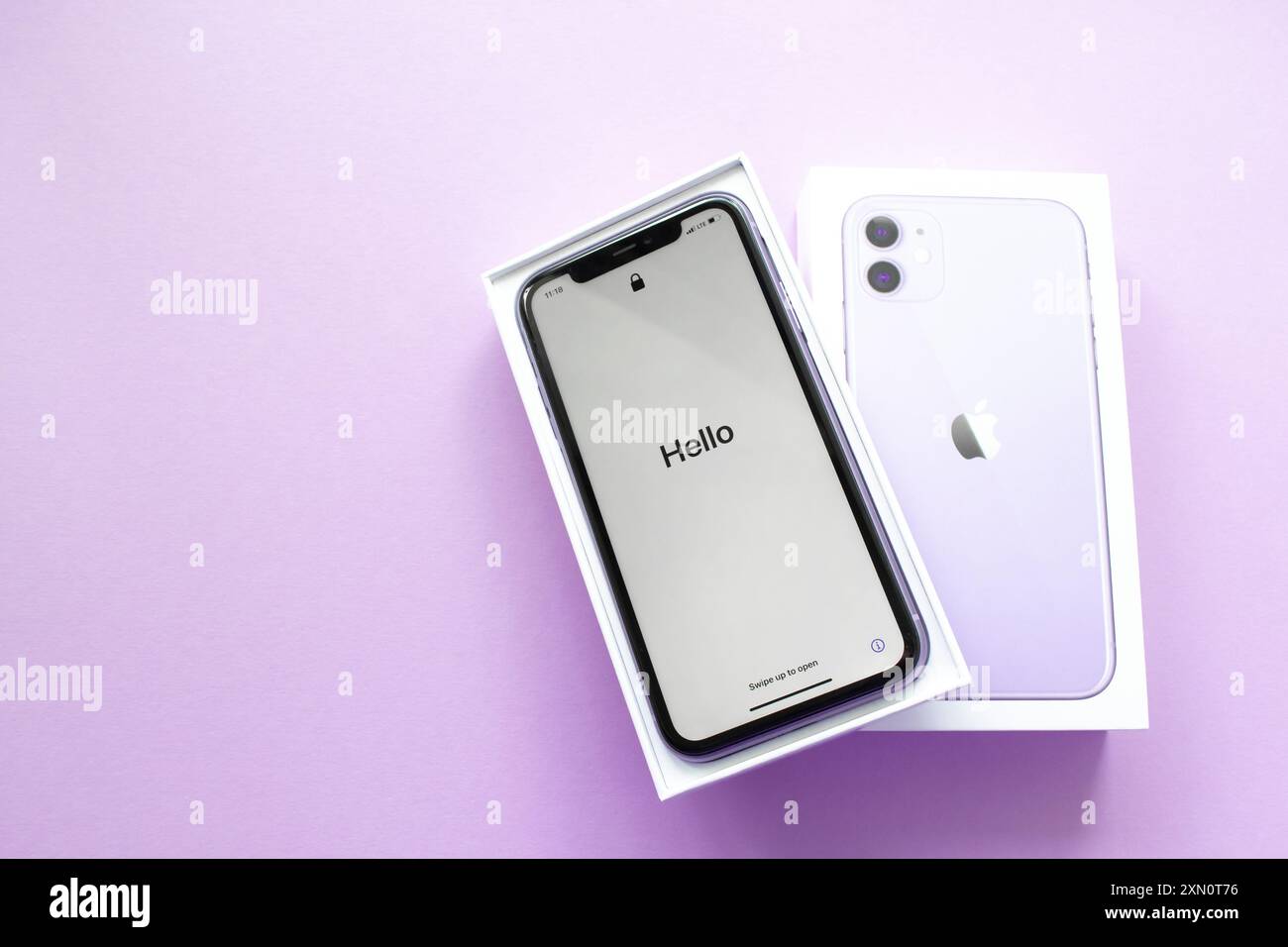 Mosca, Russia, maggio 2021: Nuovo iPhone 12 di colore viola in scatola aperta con marchio su sfondo lilla. Sullo schermo dell'iPhone, benvenuto in inglese, salve. Copia spazio. Foto Stock