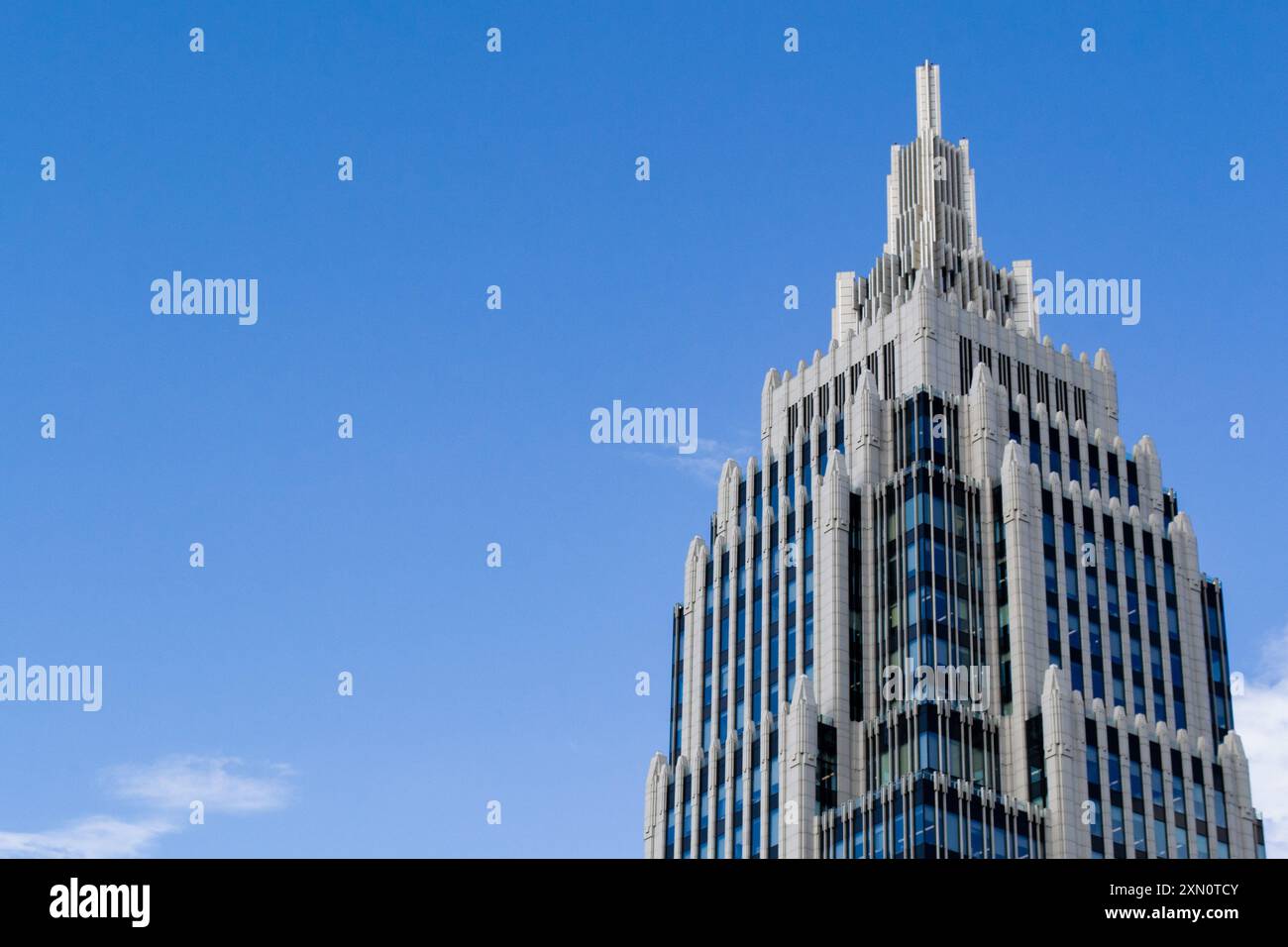 Una torre appuntita di un edificio per uffici contro un cielo blu con nuvole. Copia spazio. Foto Stock