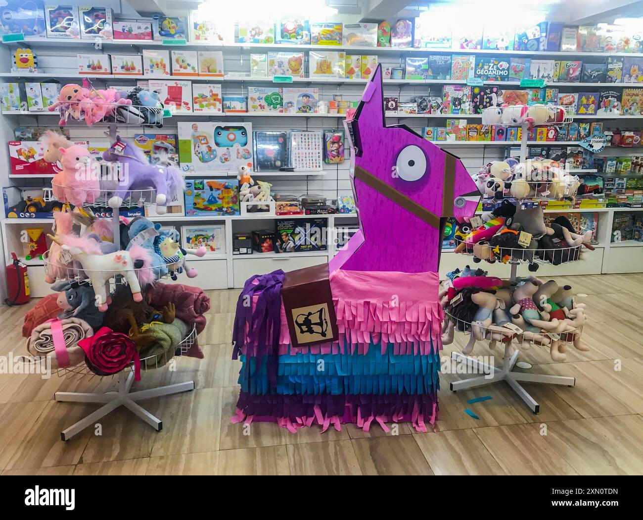Mosca, Russia, settembre 2019: Dipartimento di giochi e giocattoli per bambini in negozio: Scaffali con scatole luminose e giocattoli morbidi. Decorazioni giganti rosa penata Lama Foto Stock