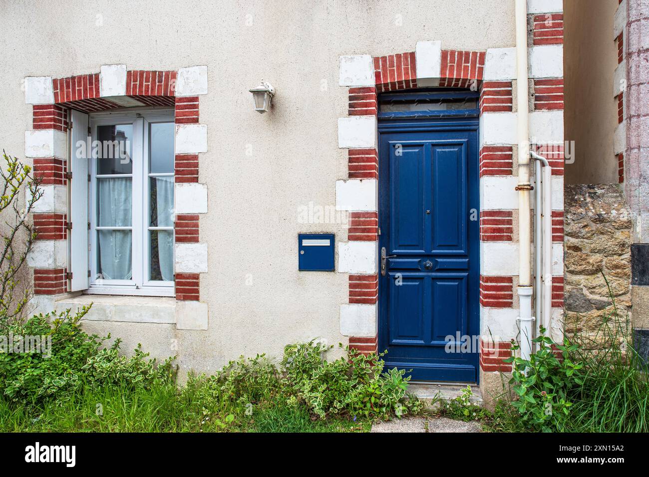 Porta d'ingresso blu di una tipica casa bianca sul mare con un contorno di mattoni rossi e bianchi e una cassetta delle lettere blu. Foto Stock