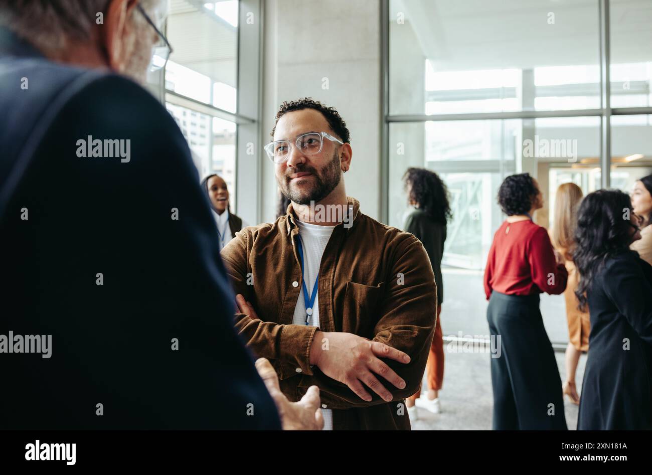 Colleghi professionisti impegnati nel networking e nella socializzazione in un evento aziendale, promuovendo connessioni e conversazioni in un moderno setti aziendale Foto Stock